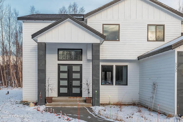 snow covered property entrance featuring french doors