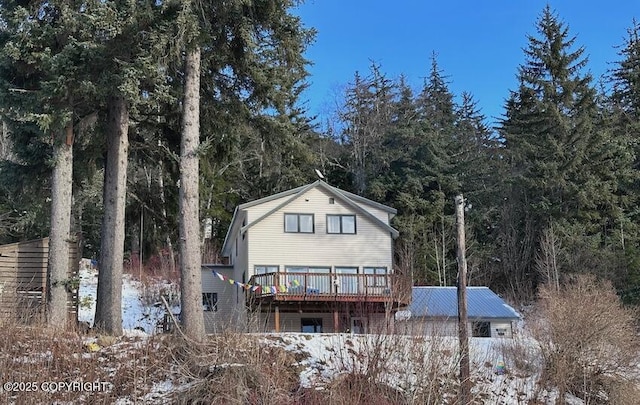 snow covered rear of property with a deck