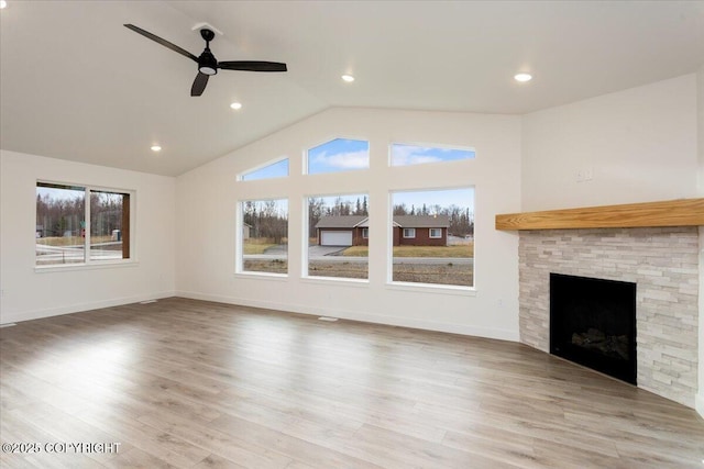 unfurnished living room featuring a stone fireplace, a ceiling fan, baseboards, vaulted ceiling, and light wood-type flooring