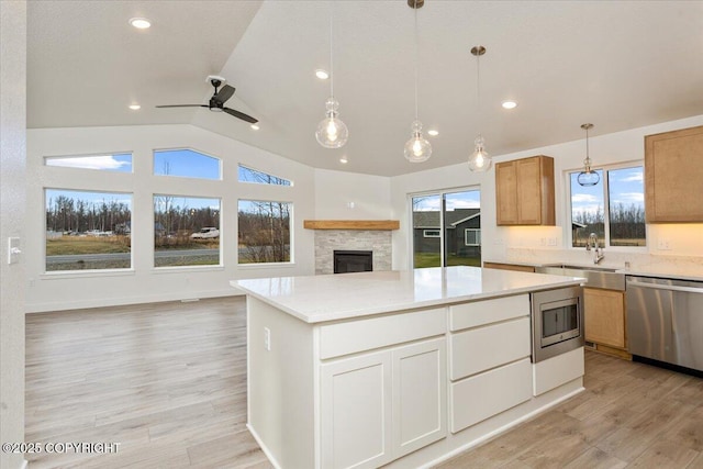 kitchen featuring sink, light hardwood / wood-style flooring, pendant lighting, stainless steel appliances, and white cabinets