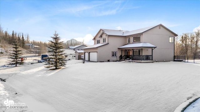 snow covered property featuring a garage and a porch