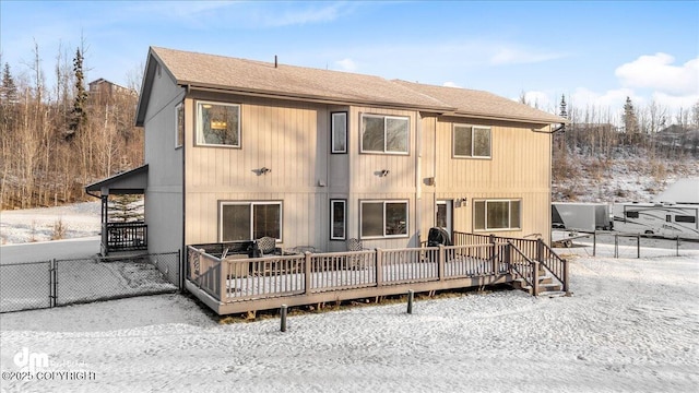 snow covered rear of property with a deck