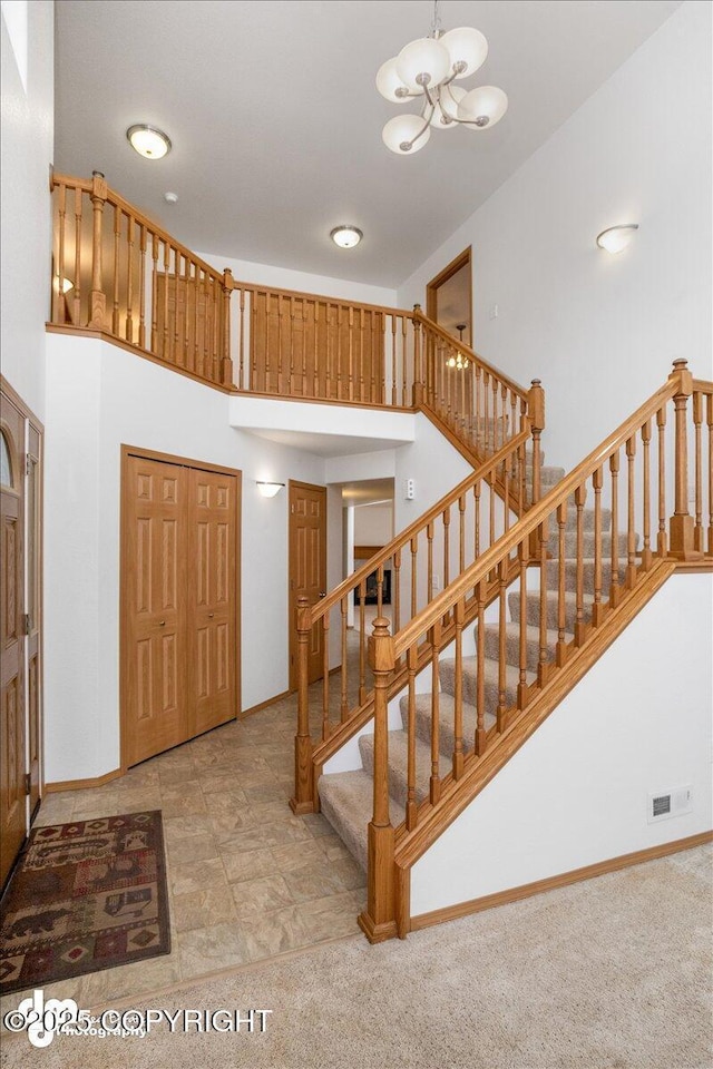 stairway featuring a chandelier, a high ceiling, and carpet flooring