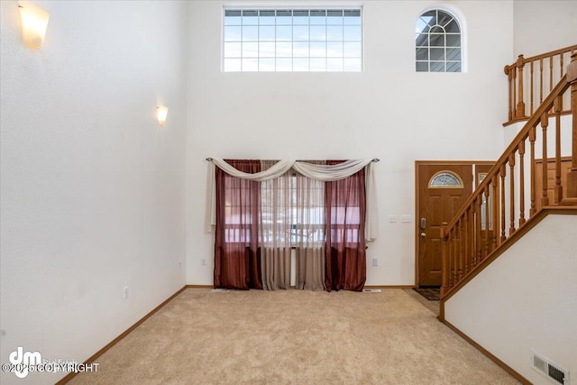 carpeted entrance foyer featuring a towering ceiling