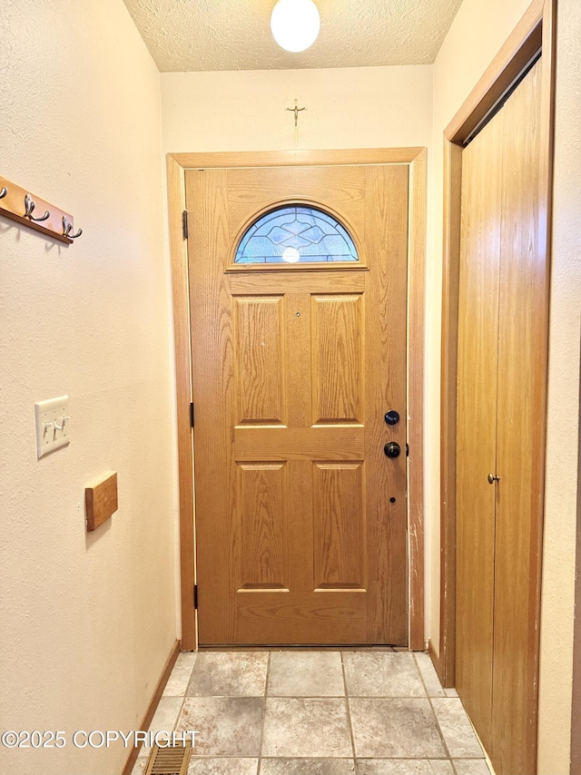 doorway with a textured ceiling and baseboards