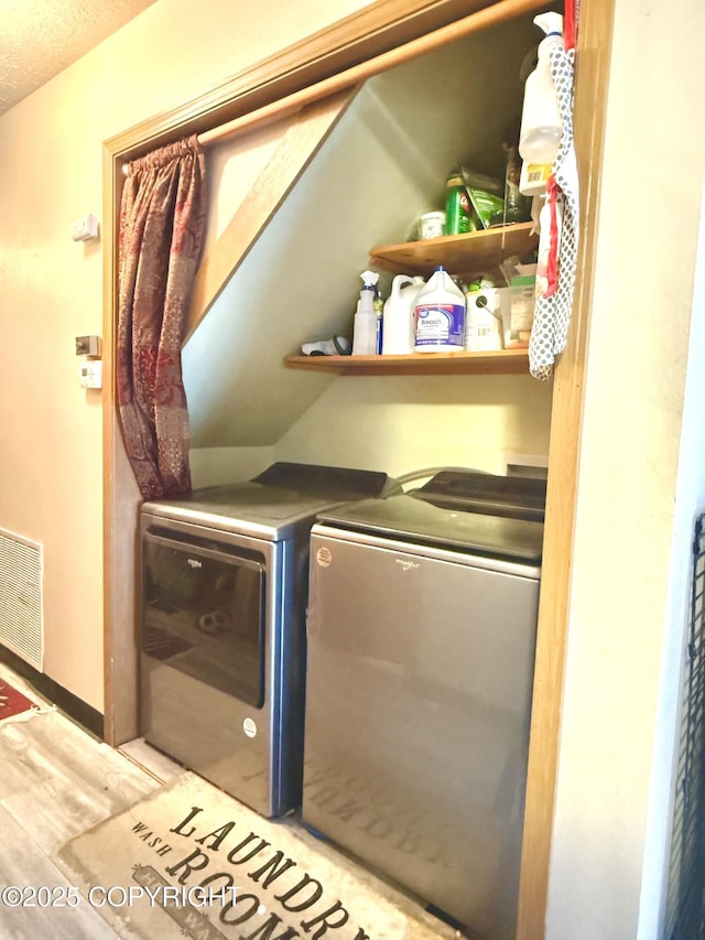 laundry area featuring light wood-type flooring, laundry area, visible vents, and washer and clothes dryer