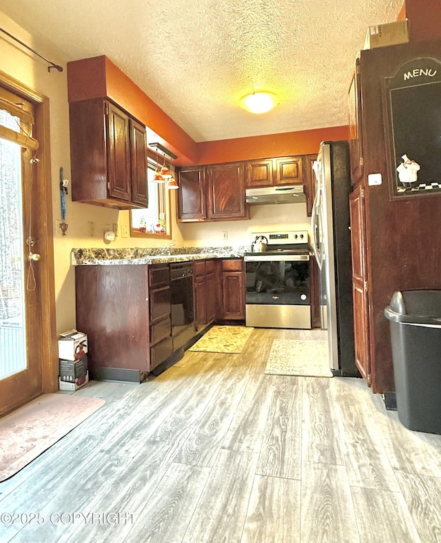 kitchen featuring light stone counters, light wood-style flooring, appliances with stainless steel finishes, a textured ceiling, and under cabinet range hood