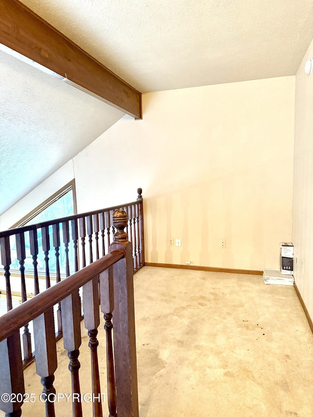 hall with carpet floors, vaulted ceiling with beams, a textured ceiling, and baseboards