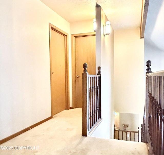 corridor with carpet floors, an upstairs landing, and baseboards