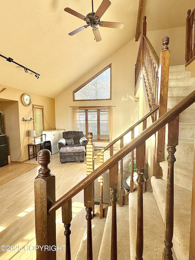 interior space with a ceiling fan, a textured ceiling, wood finished floors, high vaulted ceiling, and stairs