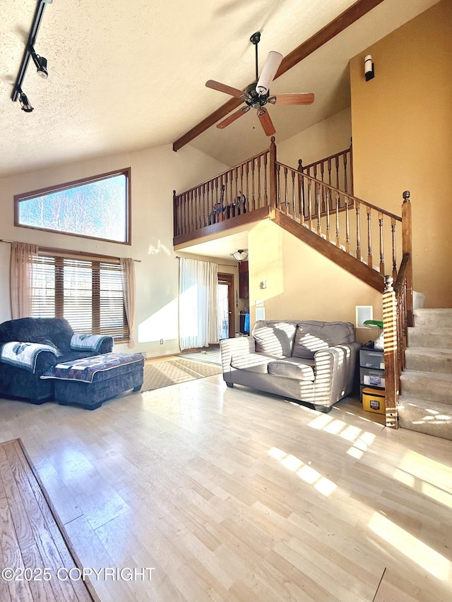 living room featuring light wood-type flooring, a healthy amount of sunlight, a textured ceiling, and stairs