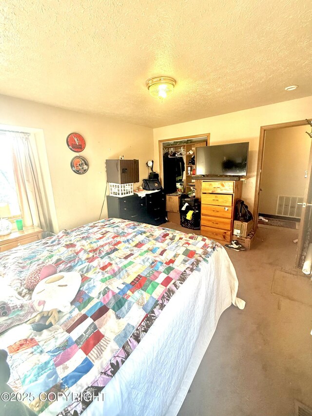 bedroom with a textured ceiling, a closet, and visible vents