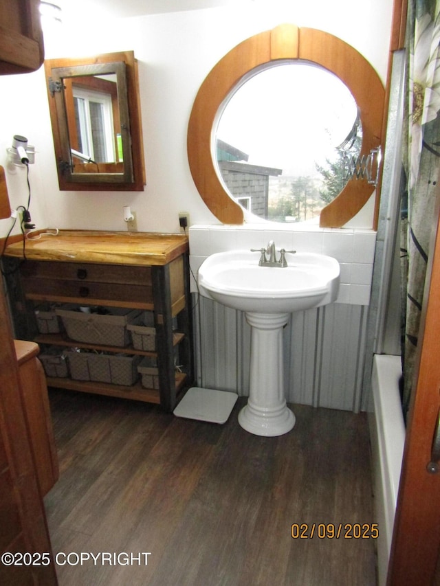 bathroom with sink, a tub, and wood-type flooring