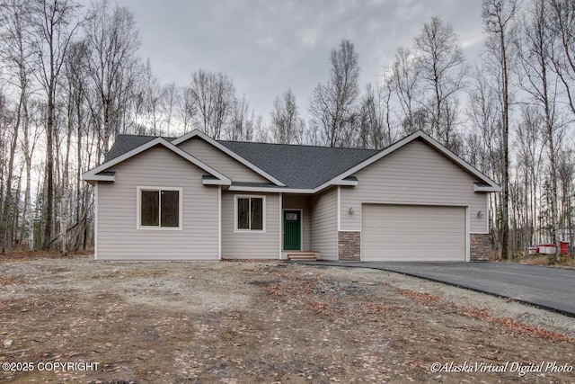 view of front of home with a garage, stone siding, driveway, and a shingled roof