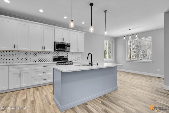 kitchen with stainless steel appliances, a sink, white cabinetry, light countertops, and decorative backsplash