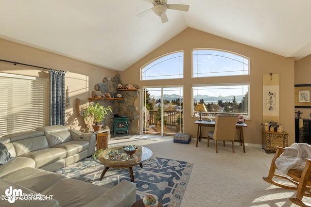 carpeted living room featuring ceiling fan, high vaulted ceiling, and a wood stove