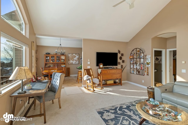 carpeted living room with ceiling fan with notable chandelier and high vaulted ceiling