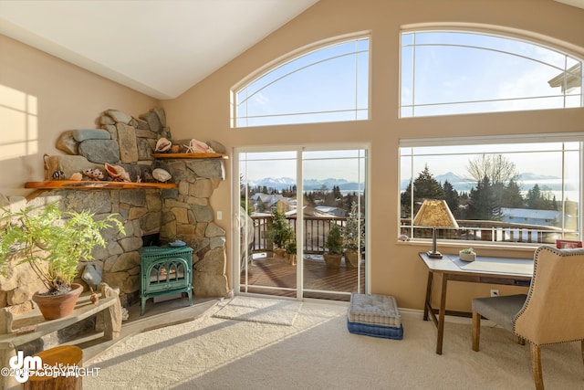 interior space featuring lofted ceiling, a mountain view, a wood stove, and carpet