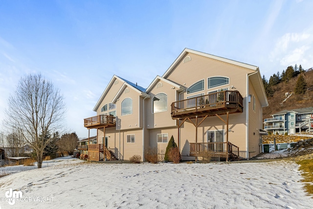 snow covered house featuring a wooden deck