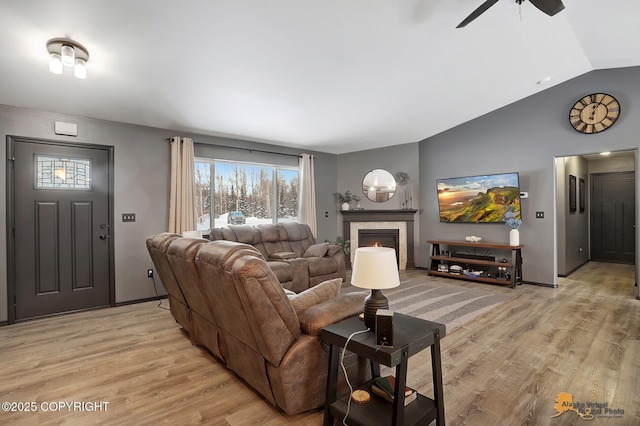 living room with ceiling fan, vaulted ceiling, and light wood-type flooring