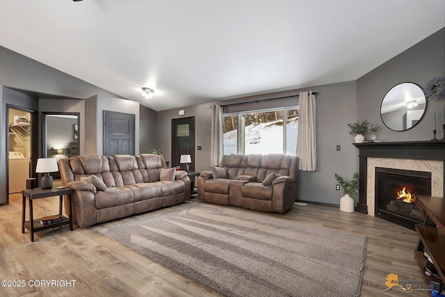 living room featuring washer / clothes dryer, vaulted ceiling, and hardwood / wood-style floors