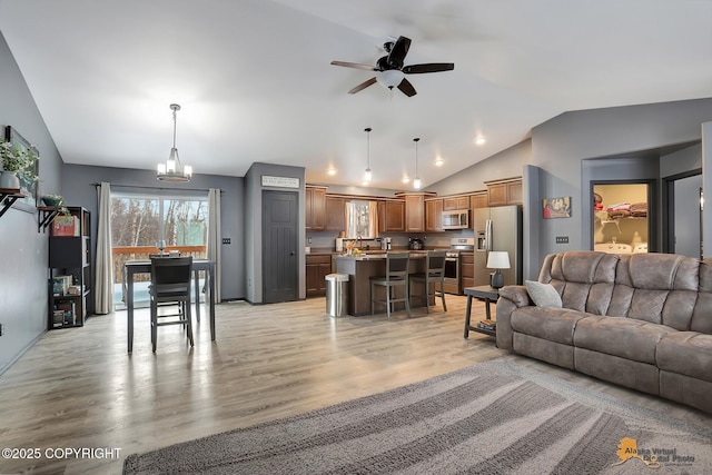 living room featuring lofted ceiling, sink, ceiling fan with notable chandelier, and light hardwood / wood-style flooring