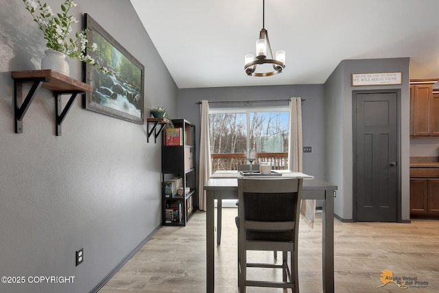 dining space featuring vaulted ceiling, a chandelier, and light hardwood / wood-style floors