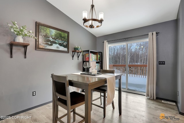 dining area featuring a notable chandelier, vaulted ceiling, and light hardwood / wood-style floors