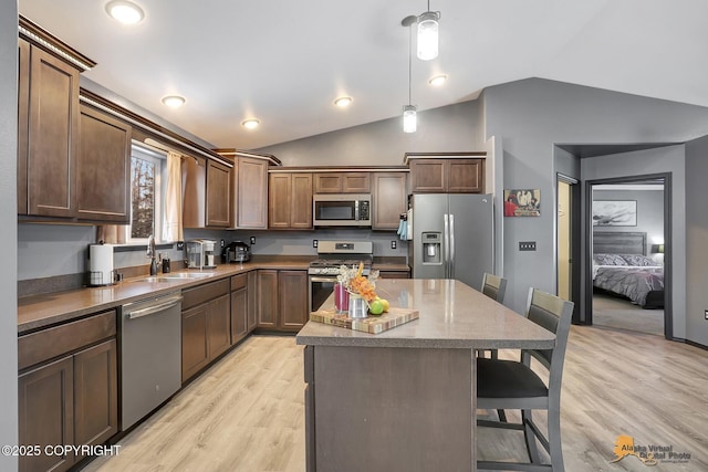 kitchen with a kitchen island, a breakfast bar, pendant lighting, sink, and stainless steel appliances