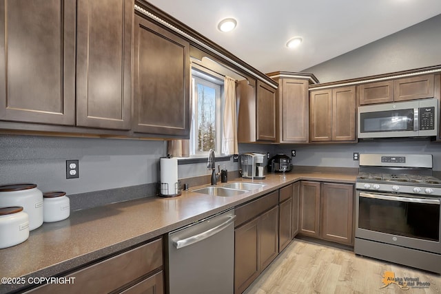 kitchen with sink, stainless steel appliances, dark brown cabinetry, light hardwood / wood-style floors, and vaulted ceiling