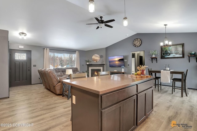 kitchen featuring lofted ceiling, decorative light fixtures, light hardwood / wood-style flooring, and a kitchen island