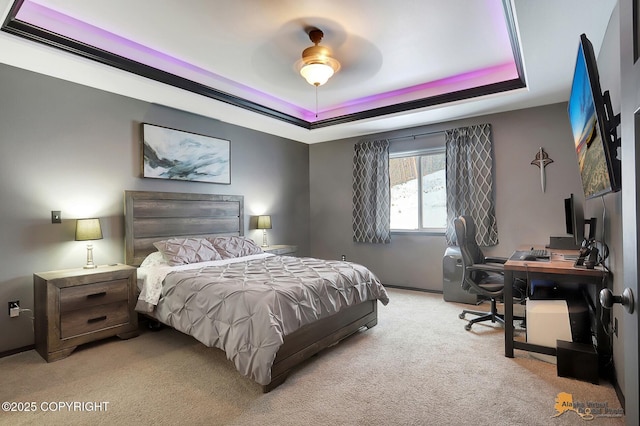 carpeted bedroom with ceiling fan and a tray ceiling