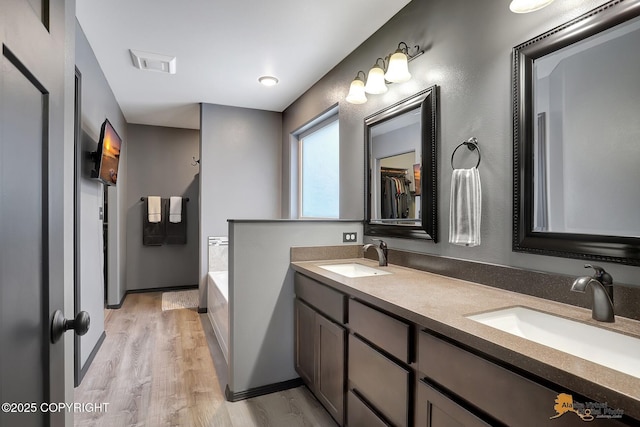 bathroom featuring vanity, a bath, and wood-type flooring