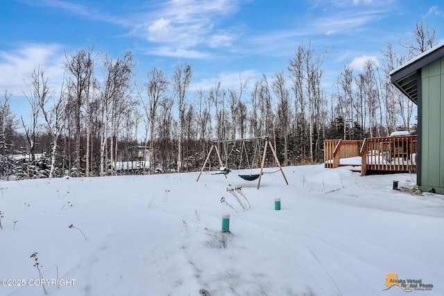 yard covered in snow featuring a deck and a playground