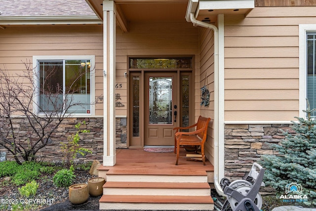 property entrance with stone siding and a shingled roof