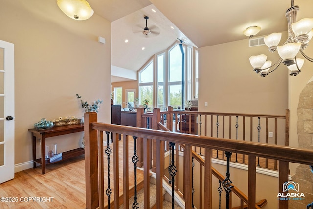 hallway with an upstairs landing, a chandelier, vaulted ceiling, and light wood finished floors
