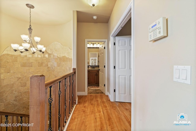 corridor with a chandelier and light wood finished floors