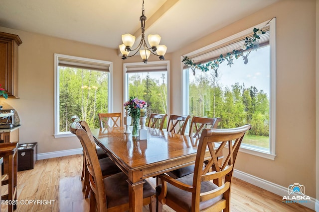 dining room with a chandelier, baseboards, and light wood-style floors