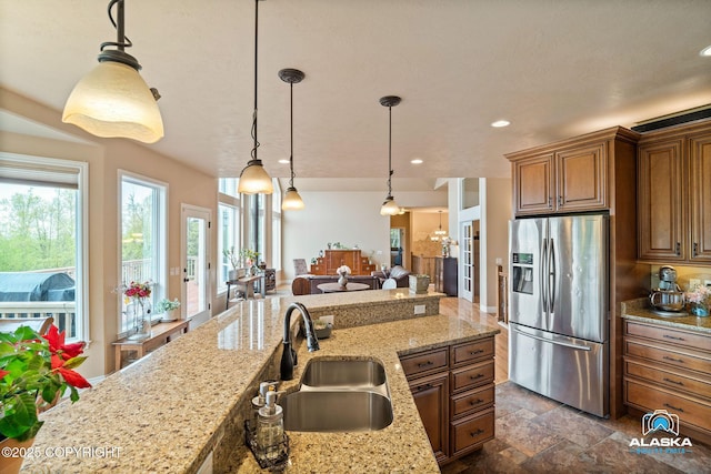 kitchen featuring stainless steel refrigerator with ice dispenser, a sink, brown cabinets, hanging light fixtures, and recessed lighting