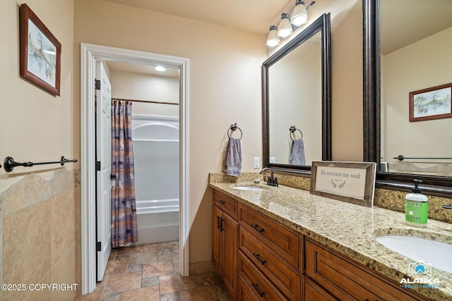 bathroom with stone finish floors, double vanity, and shower / tub combo with curtain