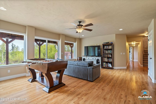 rec room with ceiling fan, baseboards, light wood-style floors, recessed lighting, and a textured ceiling