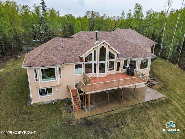 rear view of property with a forest view, a wooden deck, a yard, stairway, and a shingled roof
