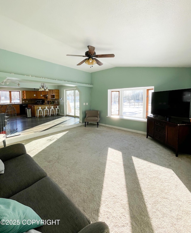 living room with carpet floors, baseboards, vaulted ceiling, and a ceiling fan