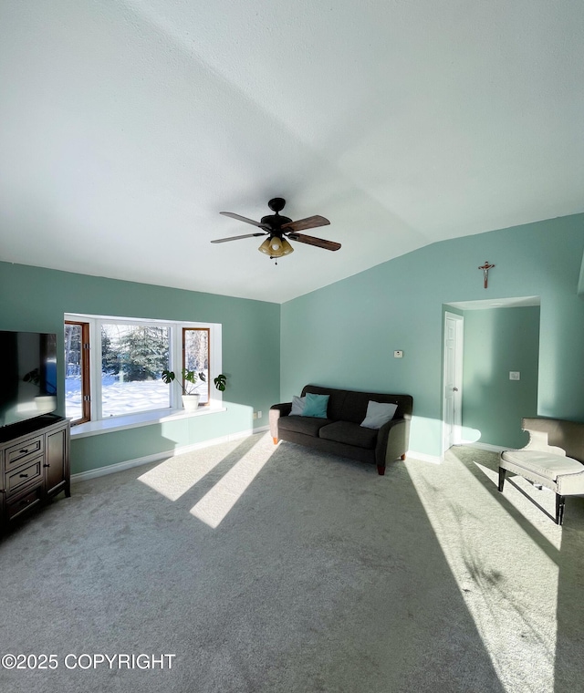 living area featuring carpet floors, baseboards, a ceiling fan, and lofted ceiling