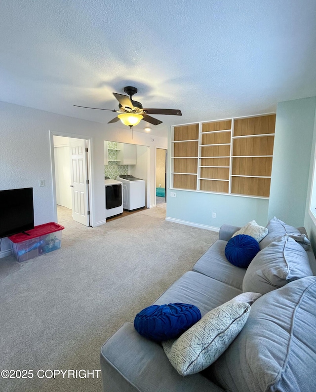 living room featuring baseboards, a ceiling fan, a textured ceiling, washer and dryer, and carpet floors