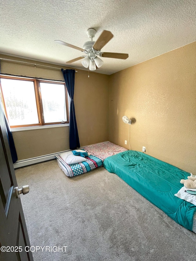 unfurnished bedroom featuring a ceiling fan, a textured wall, a baseboard radiator, a textured ceiling, and carpet floors