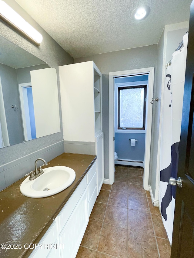 bathroom featuring a textured ceiling, a baseboard radiator, toilet, vanity, and tile patterned floors