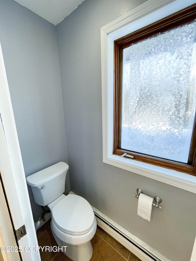 bathroom with baseboard heating, toilet, and tile patterned floors