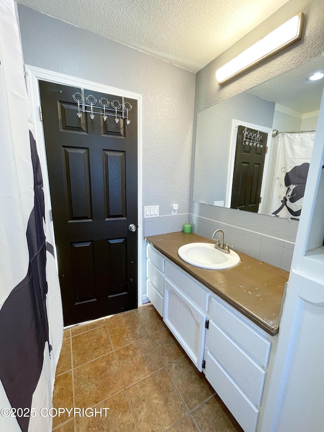 bathroom featuring a textured ceiling, a textured wall, vanity, and tile patterned floors