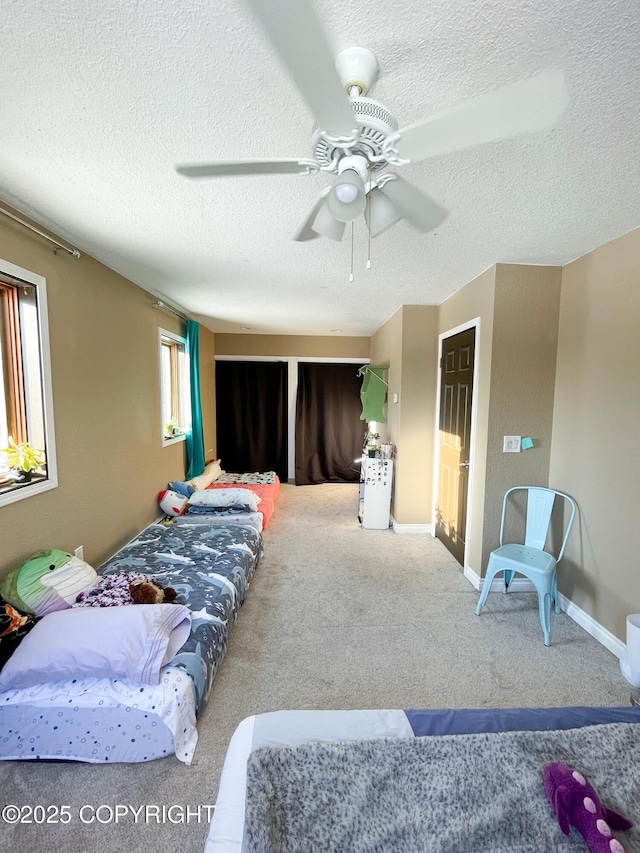 bedroom with a textured ceiling, baseboards, a ceiling fan, and carpet flooring